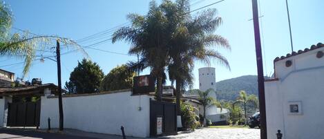 Une rue tranquille avec un bâtiment blanc, un palmier et une montagne en arrière-plan.