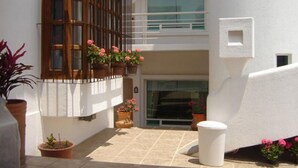 A building with a balcony, potted plants, and a tiled patio area.