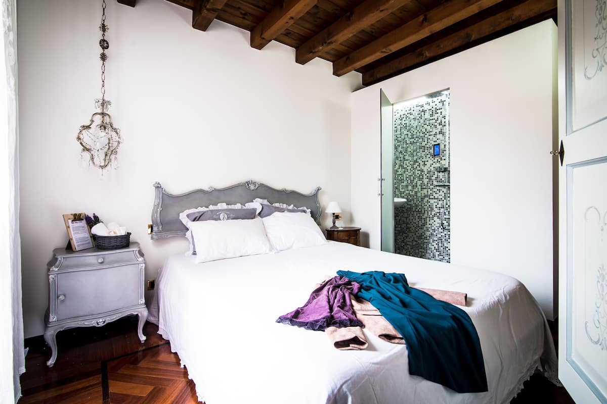 A bedroom with a bed, a nightstand, a chandelier, and a patterned wall.