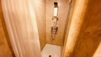 Et aflangt badeværelse med et hvidt toilet, et håndklædetørrestativ og et brusepanel.