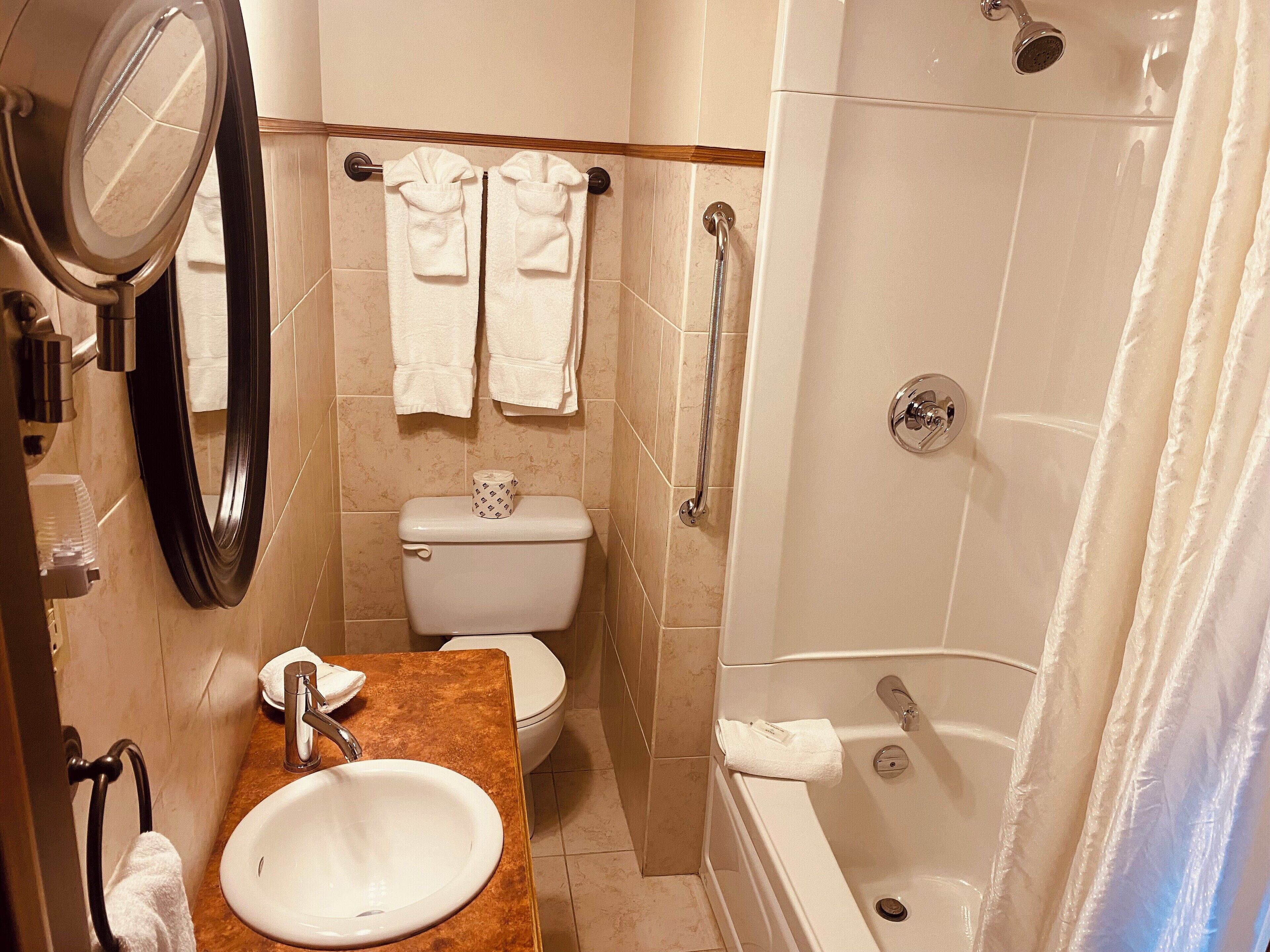 Een badkamer met een wastafel, toilet, badkuip en spiegel.