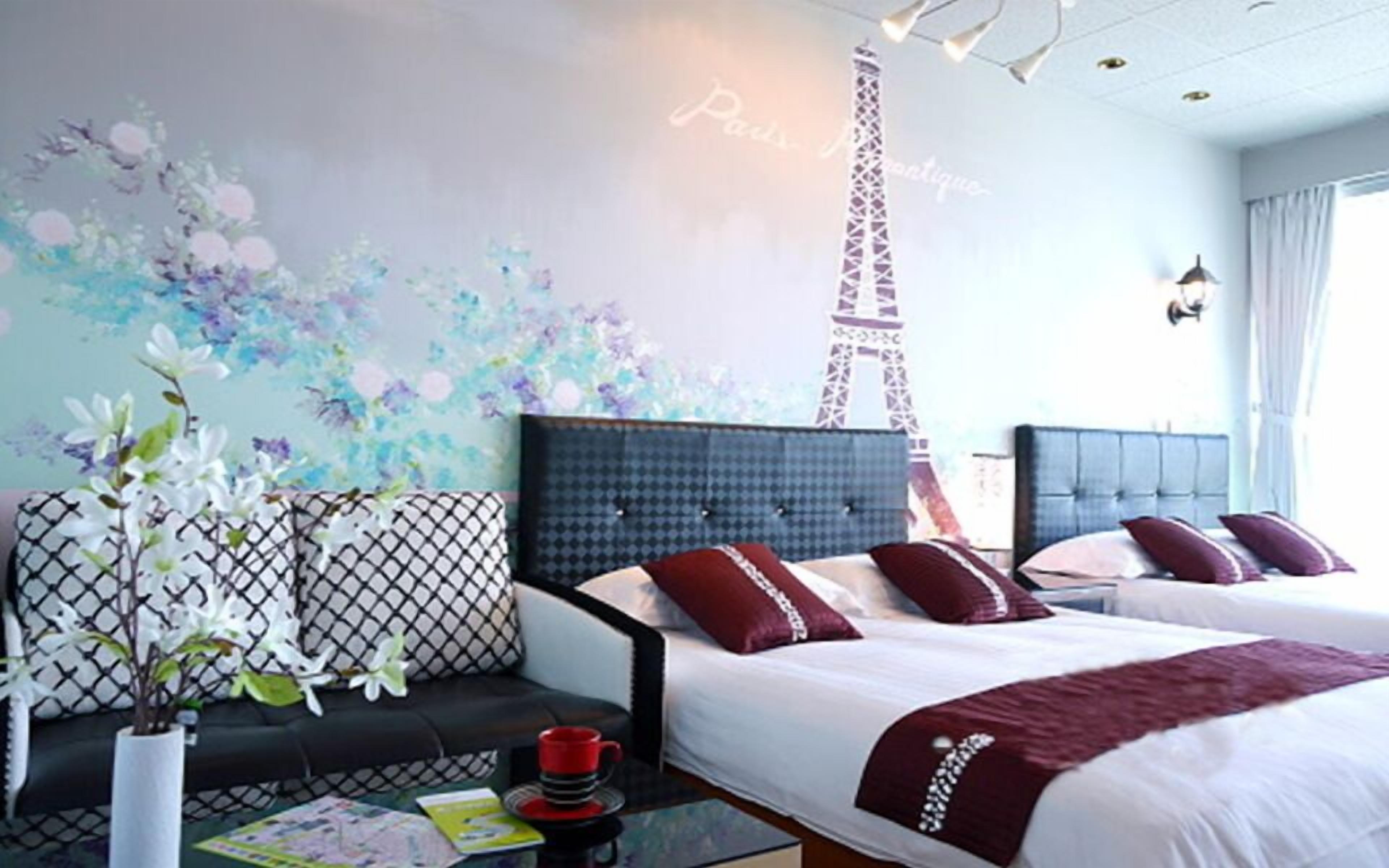 Una habitación de hotel con cama, sofá, mesa de centro y una pared decorada con un mural floral.