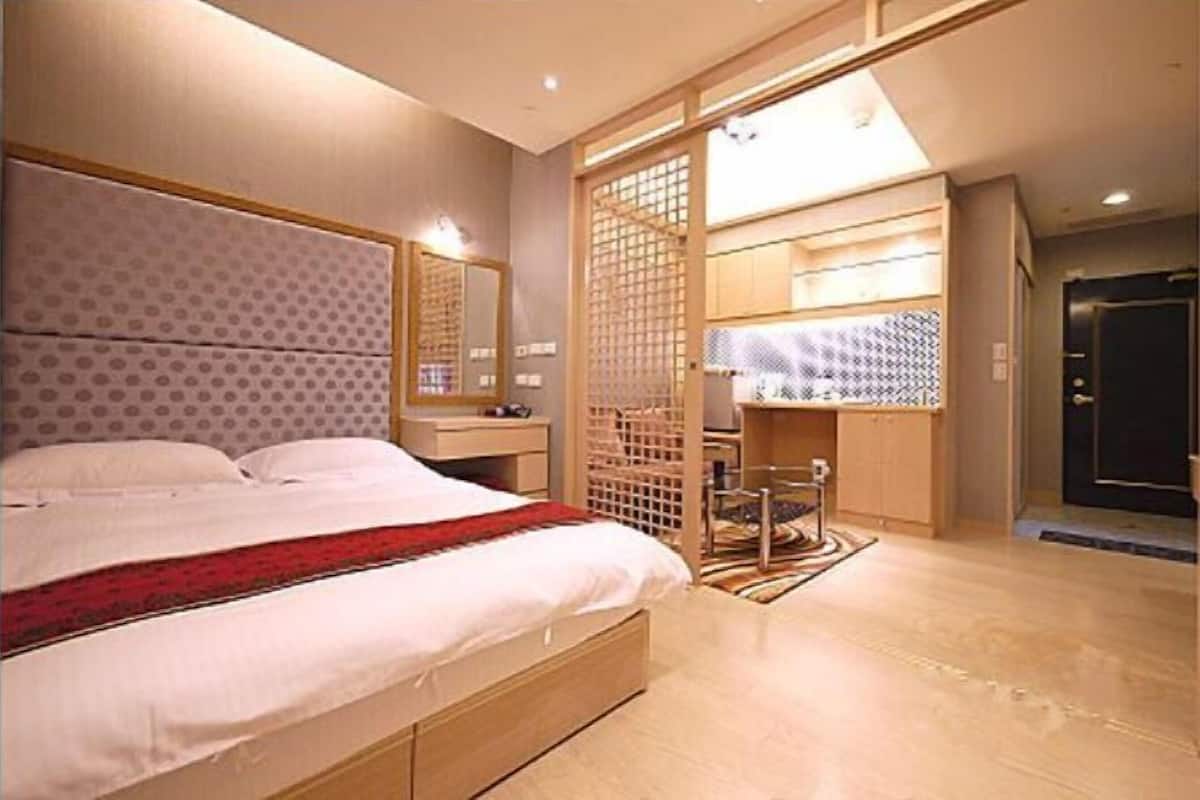 A bedroom with a bed, a bedside table, a mirror, a wardrobe, and a door.