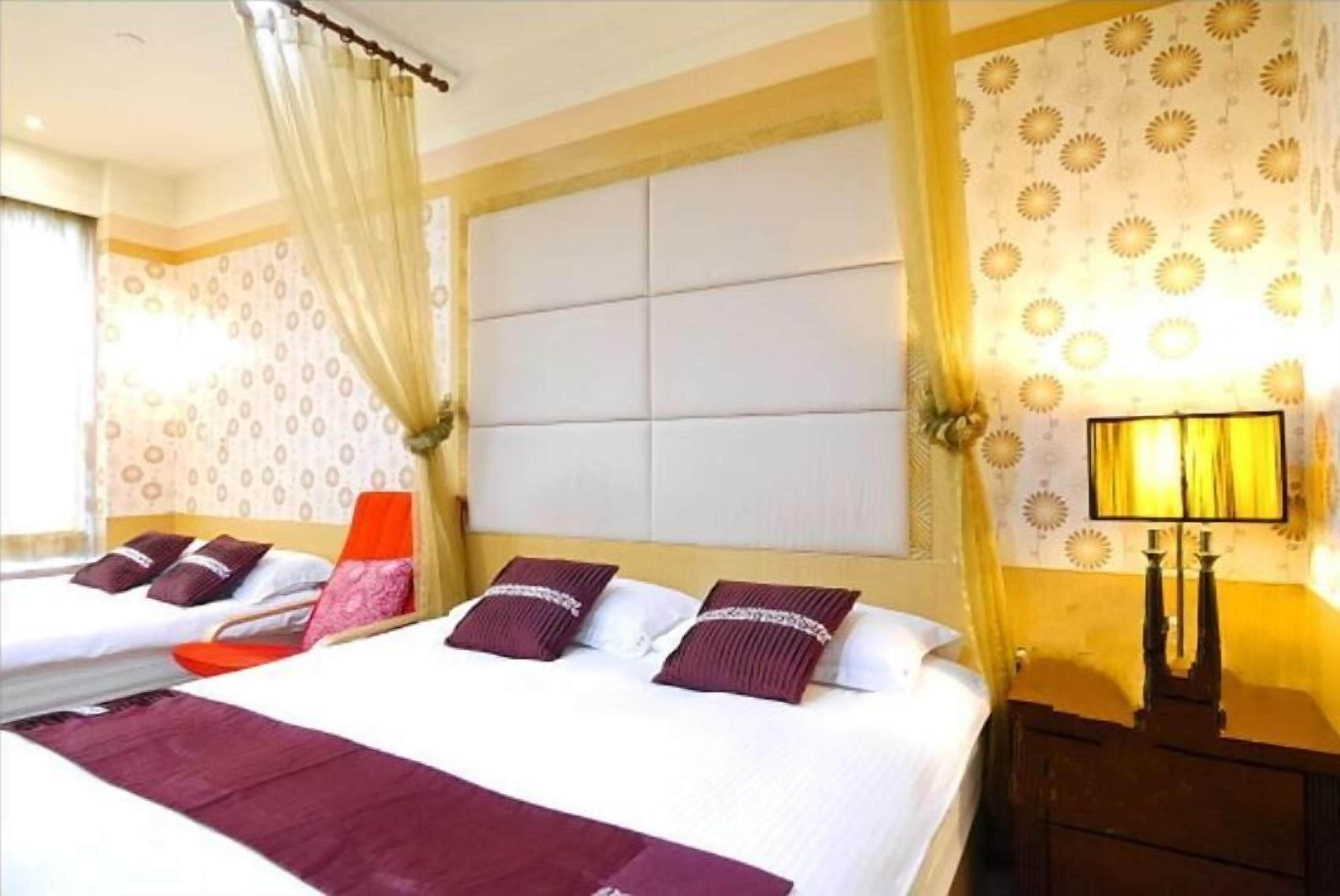 Una habitación de hotel con una cama grande, dos almohadas, una mesita de noche y una lámpara.