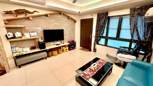 A modern living room with a flat-screen TV, a blue sofa, and a coffee table. - Anping 72 Hostel (Tainan)