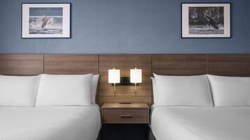 A hotel room with two beds, a wooden headboard, bedside lamps, and framed pictures on the wall.