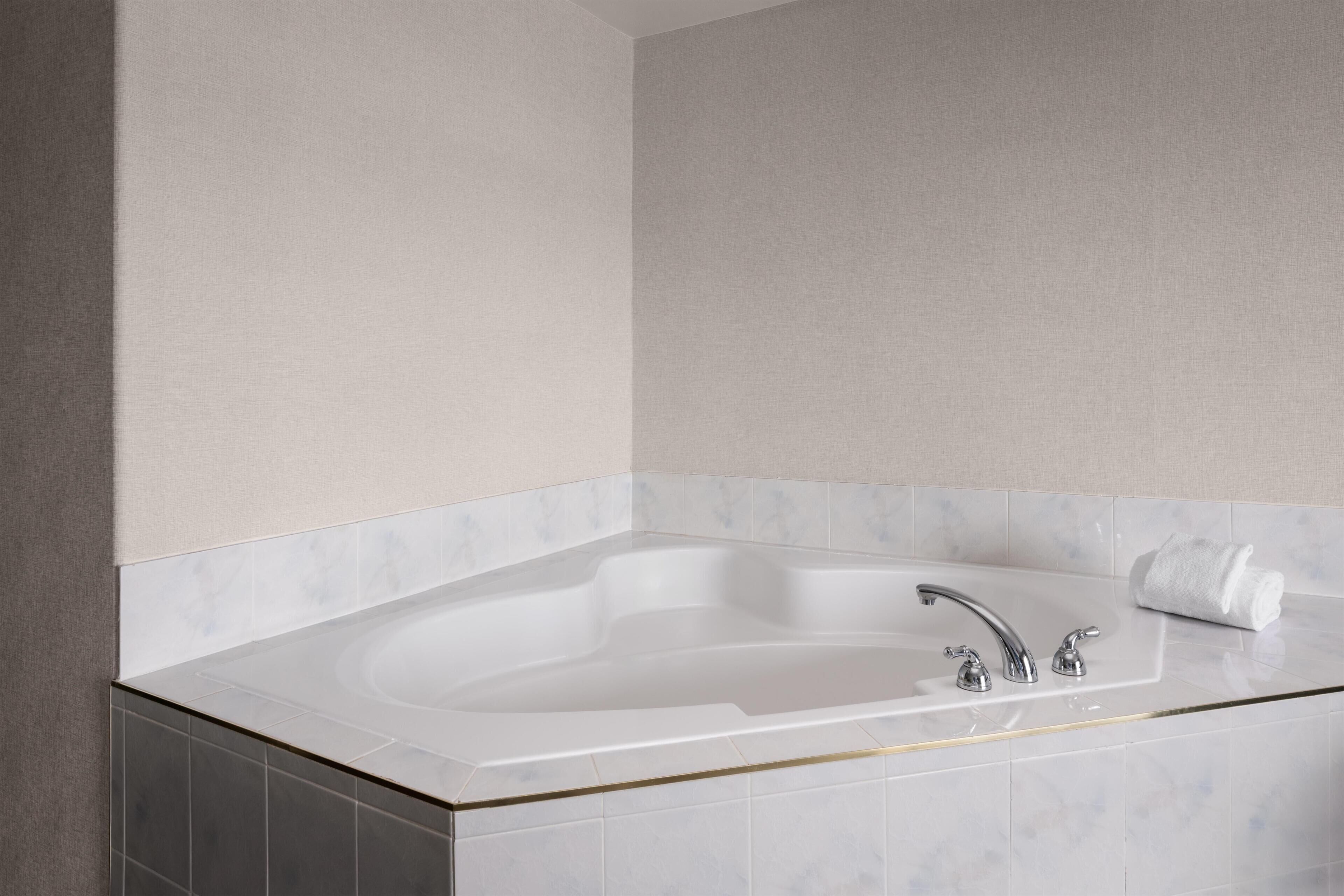 A modern bathroom with a freestanding bathtub, a single faucet, and a towel on the side.