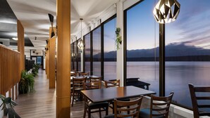 Un ristorante con ampie vetrate, arredi in legno e piante pensili.