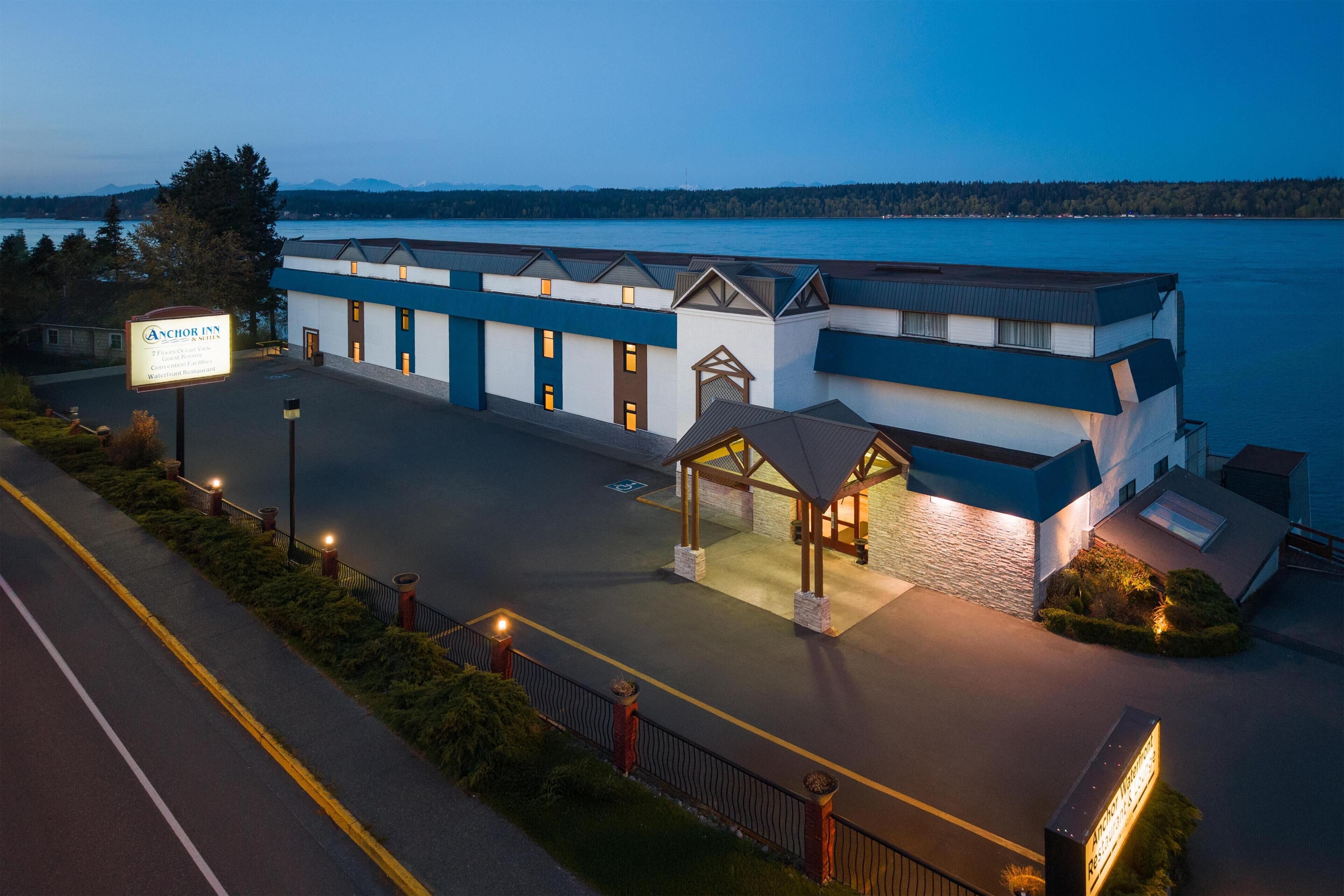 A hotel with a sign, a covered entrance, and a view of a body of water.