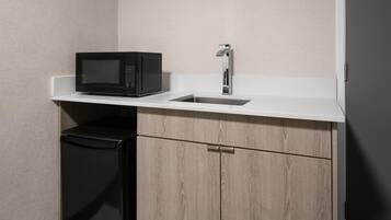A compact kitchenette with a microwave, sink, and a small refrigerator.