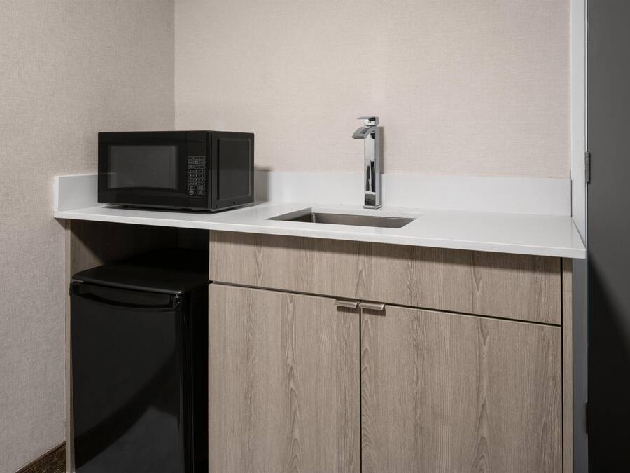 A compact kitchenette with a microwave, sink, and a small refrigerator.