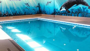An indoor swimming pool with a 'NO DIVING' sign, a dolphin mural, and a depth marker of 1.2 meters.