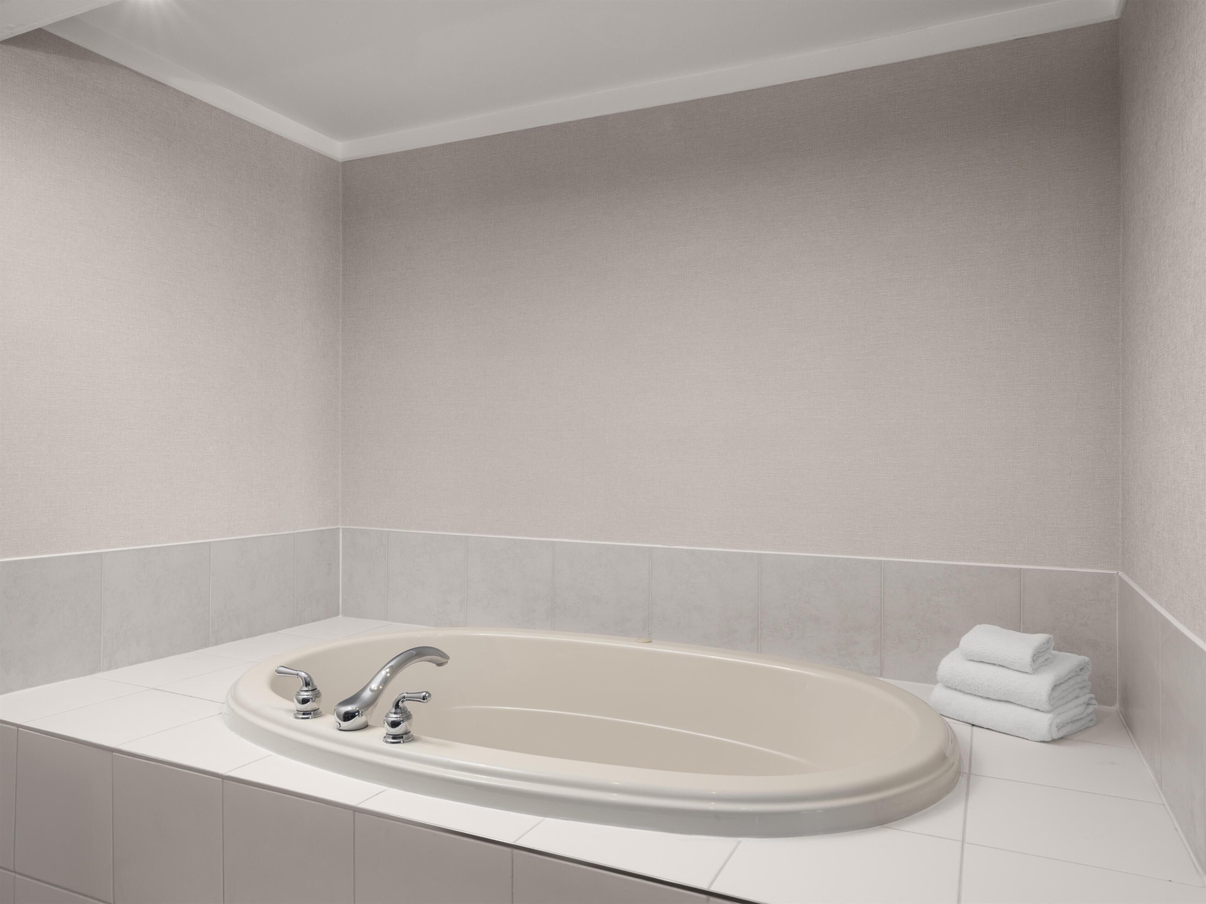 Et moderne badeværelse med et fristående badekar, et toiletbord med spejl og en stak hvide håndklæder.