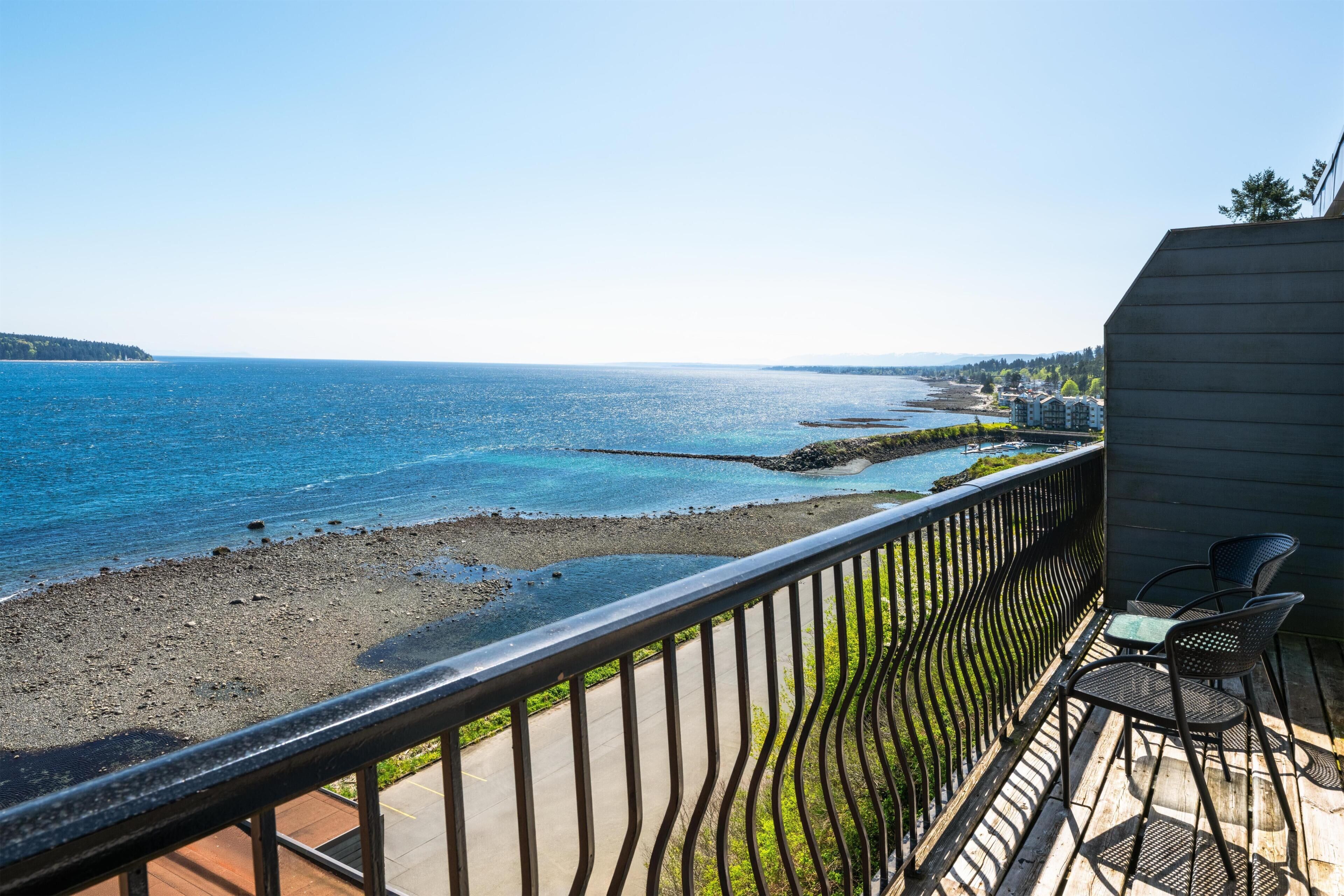 Ein Balkon mit Blick auf das Meer, einer Holzterrasse und zwei Stühlen.