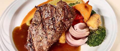 Un plato de comida con bistec, verduras y salsa.