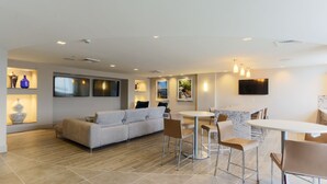 A modern living room with a sofa, a dining area with a table and chairs, and a TV mounted on the wall. - Pelicanstay in Coconut Grove Miami (Miami)