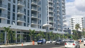 A high-rise building with multiple balconies, a clear sky, and parked cars on the street. - Pelicanstay in Coconut Grove Miami (Miami)