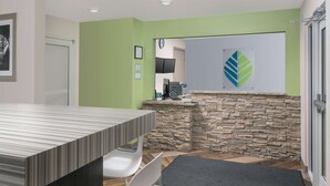 Un área de recepción con mostrador, pared de piedra, un reloj y un logotipo en la pared.