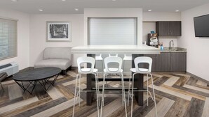 Una cocina moderna con comedor, que incluye una mesa y sillas, un sofá y un ventanal con persianas.