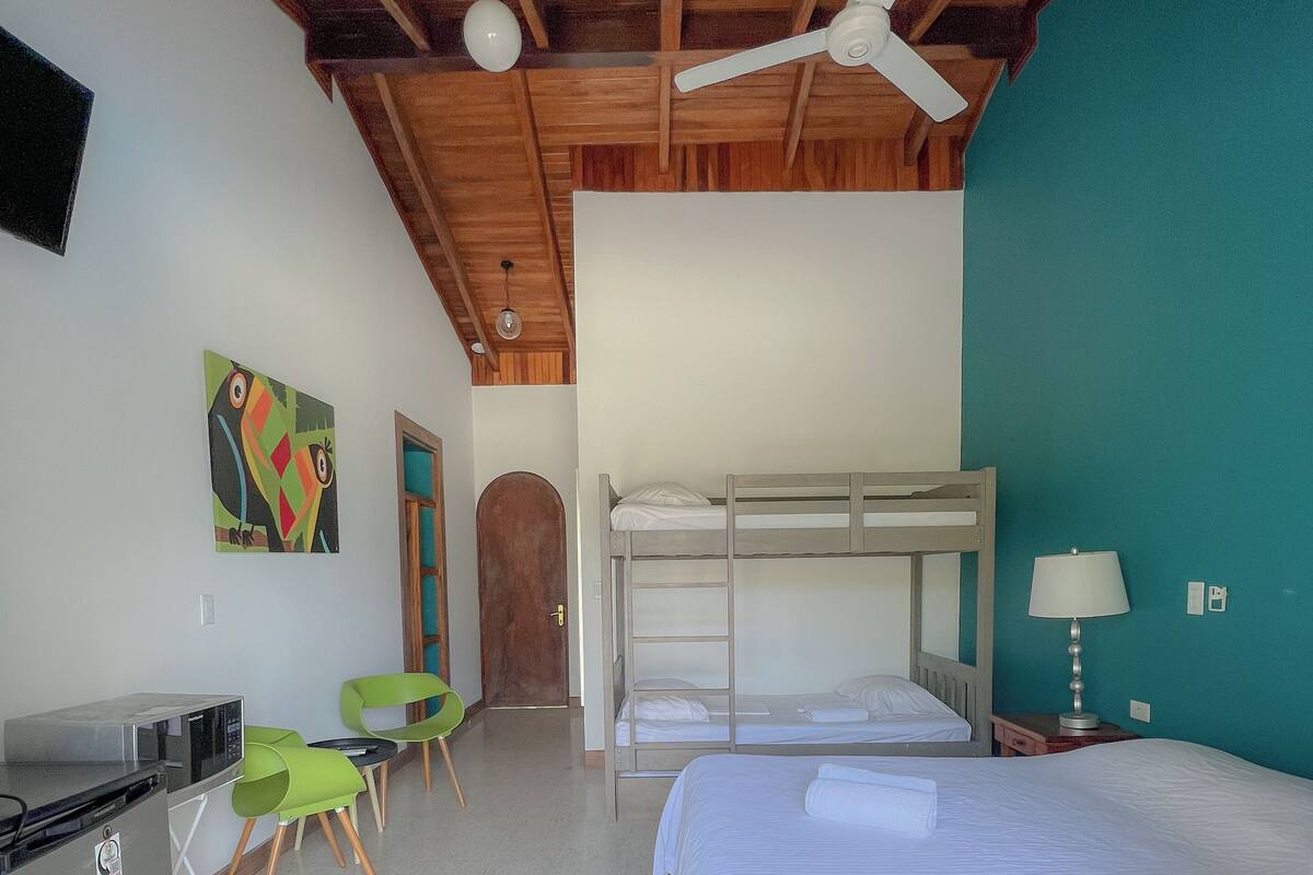 A room with bunk beds, a desk, chairs, a TV, and a ceiling fan.