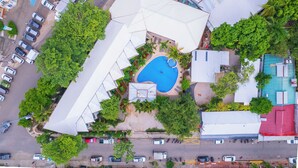 Vista aérea de um imóvel com piscina, várias vagas de estacionamento e vegetação ao redor.