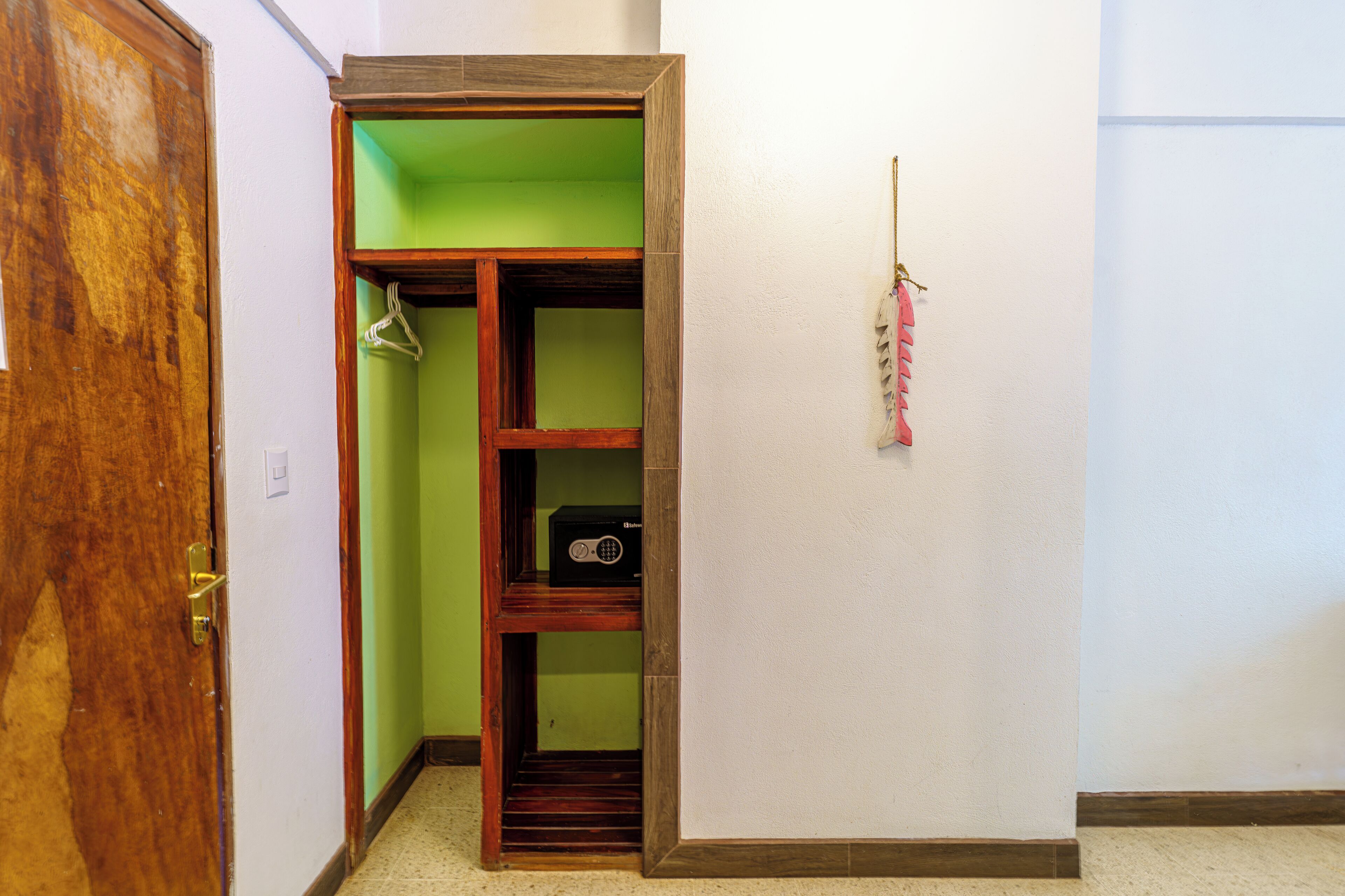 A hallway with a wooden door, a closet with green interior, and a coat rack with a pink item.