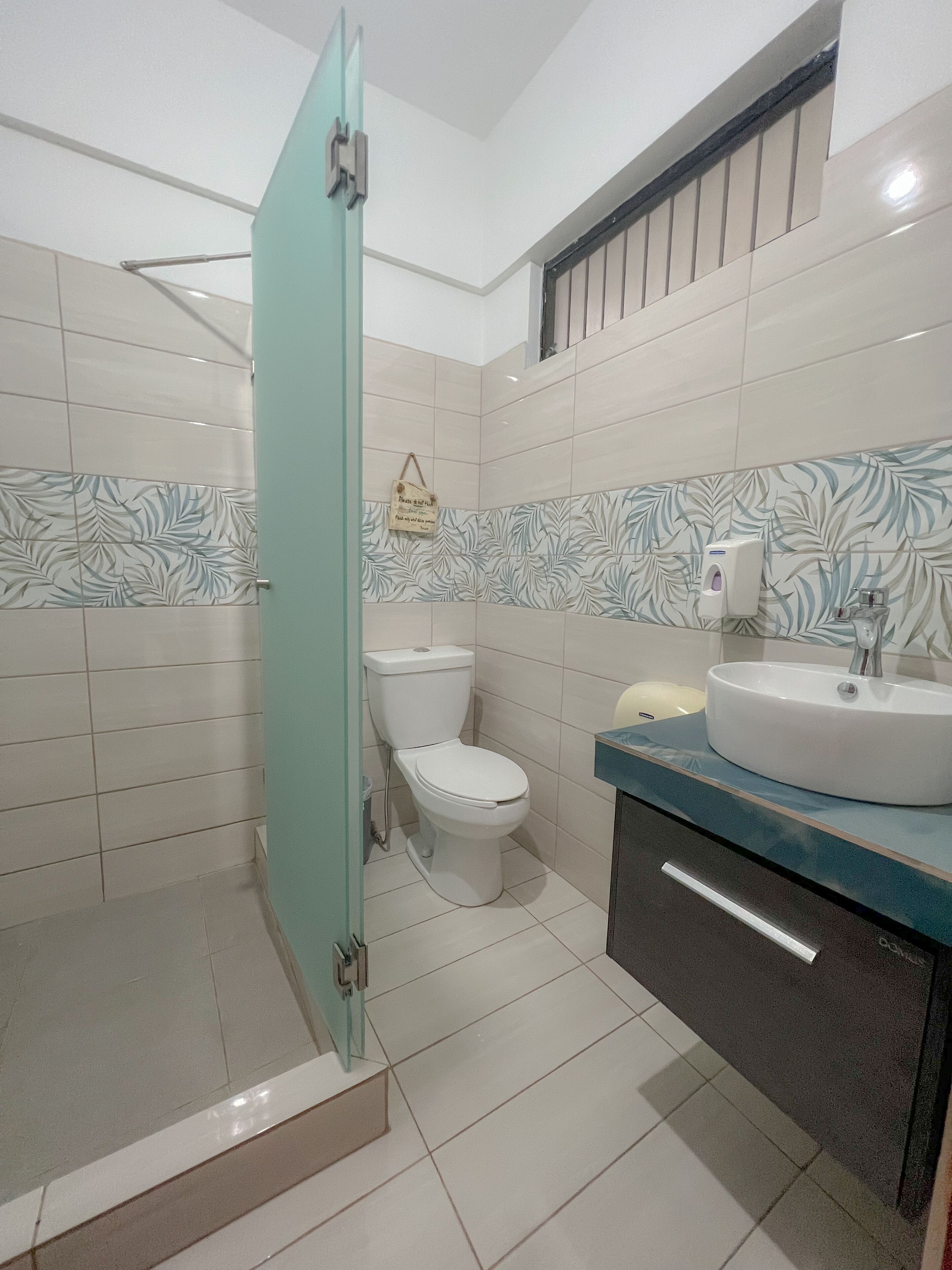 A modern bathroom with a glass shower enclosure, a toilet, and a sink with a blue countertop.