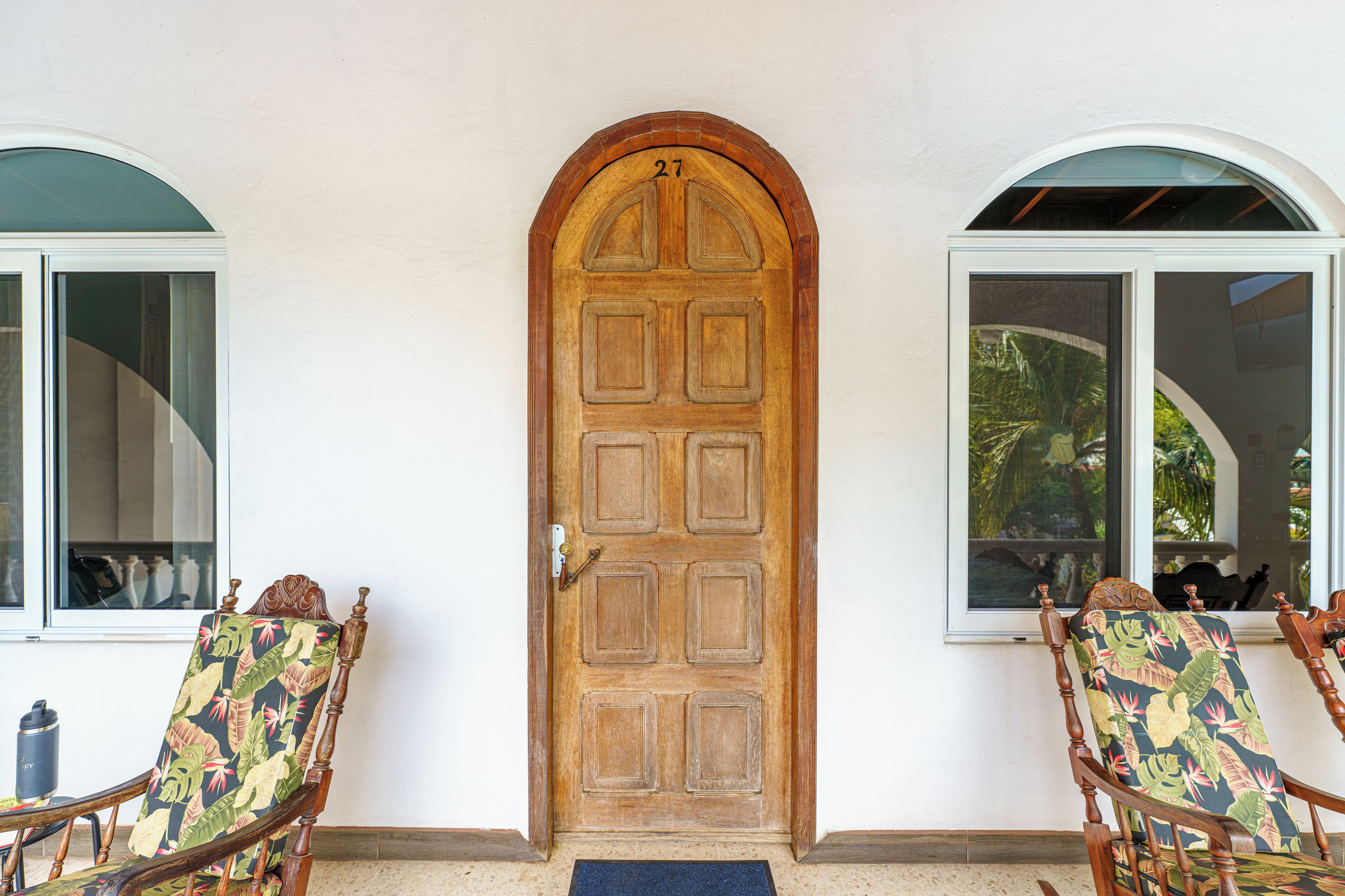 A wooden door with the number 27, flanked by two windows with arched tops.