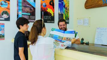 A reception desk with a man reading a brochure, surrounded by various travel posters on the wall.