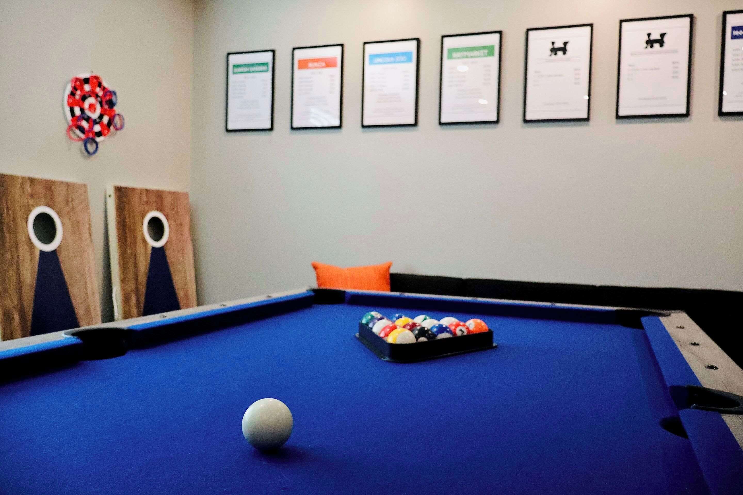 A pool table with a white cue ball, a rack of billiard balls, and framed certificates on the wall.