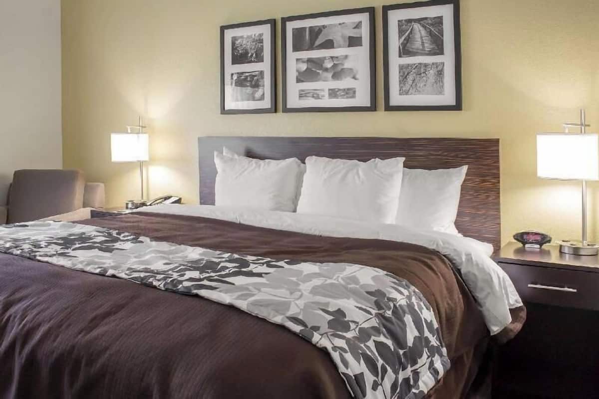 A hotel room with a bed, two bedside lamps, a nightstand, and three framed pictures on the wall.