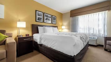 A hotel room with a large bed, a nightstand, a lamp, a chair, and a window with curtains.