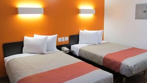 A hotel room with two beds, each with white bedding and a red accent. There are wall-mounted light fixtures on the orange wall. - Motel 6 Augusta, GA - Fort Gordon (Augusta)