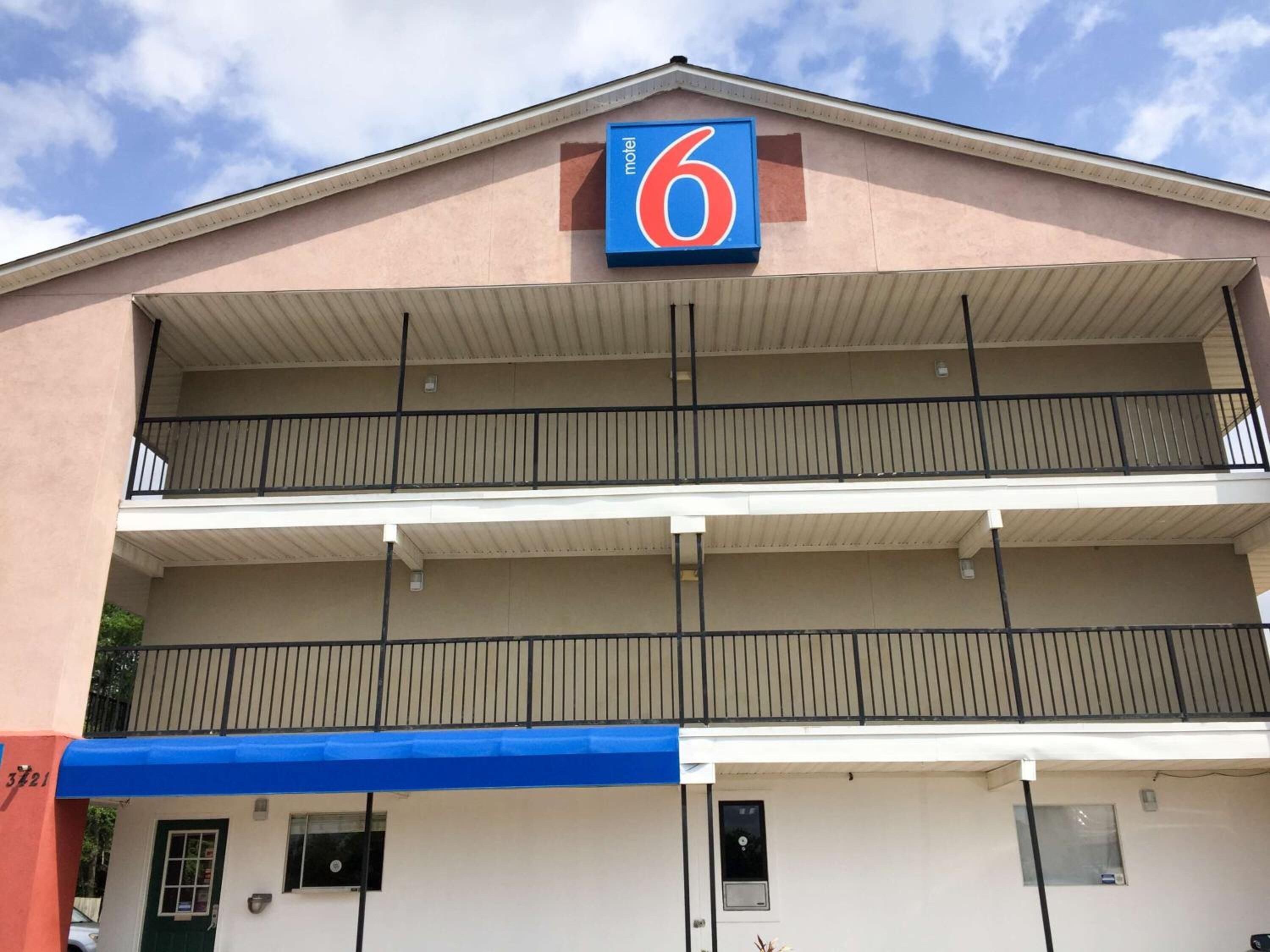 A motel with a '6' sign, two-story structure, and a blue awning over the entrance.
