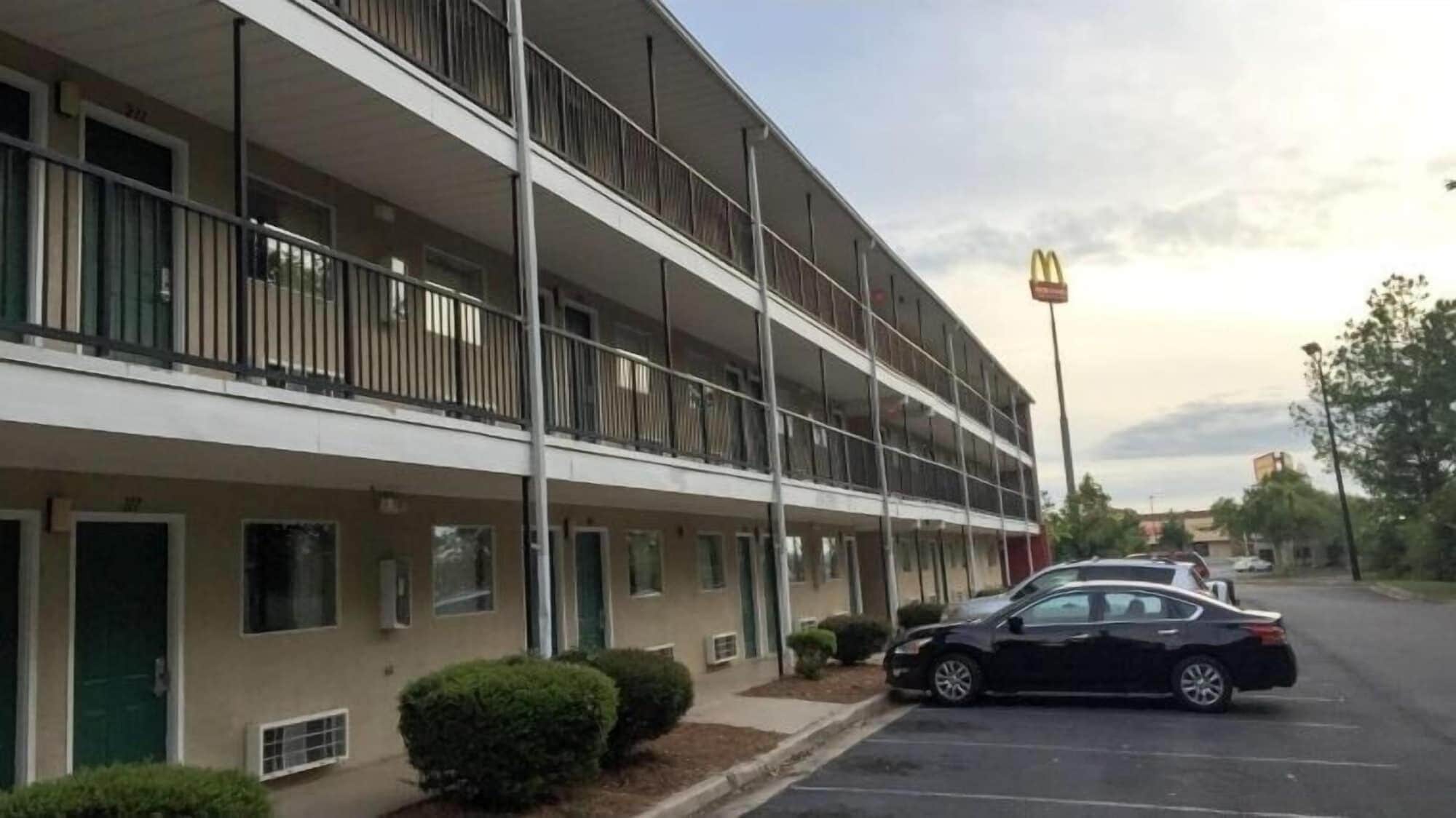 A multi-story hotel with balconies, a parking lot, and a McDonald's sign in the background.