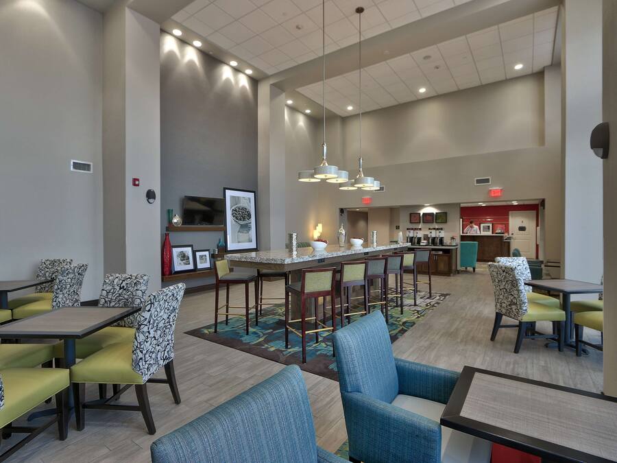 A spacious hotel lobby with a bar area, seating arrangements, and a kitchen in the background.