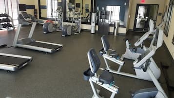 A gym with treadmills, elliptical machines, and a water dispenser.