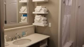 Un baño con lavamanos, espejo, toalleros y cortina de ducha.