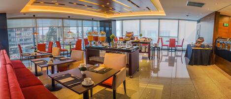 A modern restaurant with red seating, a buffet area, and a coffee station.