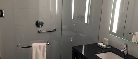 A modern bathroom with a glass shower enclosure, a black sink vanity, and a large mirror.