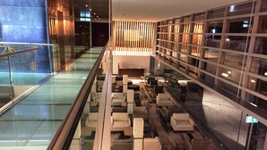 Un hall d’entrée moderne doté d’une rambarde en verre, d’un espace salon et d’un comptoir d’accueil.
