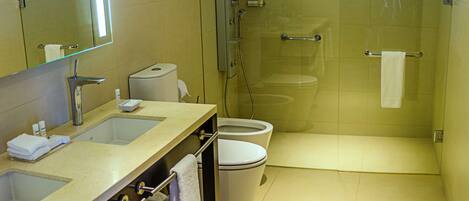 Un baño moderno con ducha envuelta en vidrio, un espejo grande y un mueble de tocador doble.