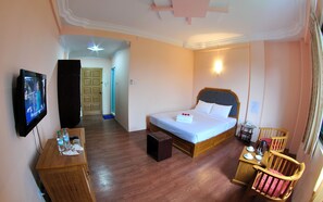 A hotel room with a bed, bedside table, TV, and a small table with cups and a thermos. - Hotel Glory (Yangon)
