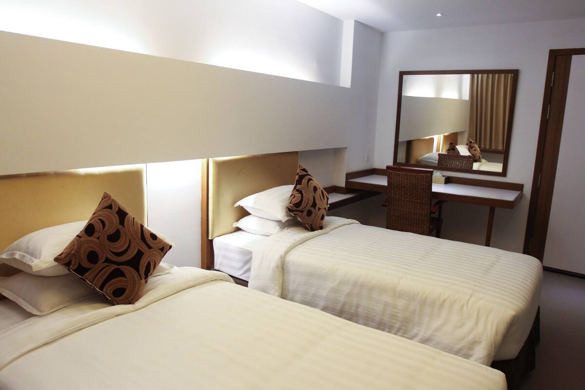 Habitación de hotel con dos camas, un escritorio y un espejo.