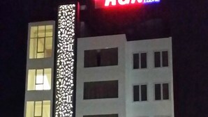 Un edificio de varios pisos con un panel decorativo vertical llamativo y un letrero que dice 