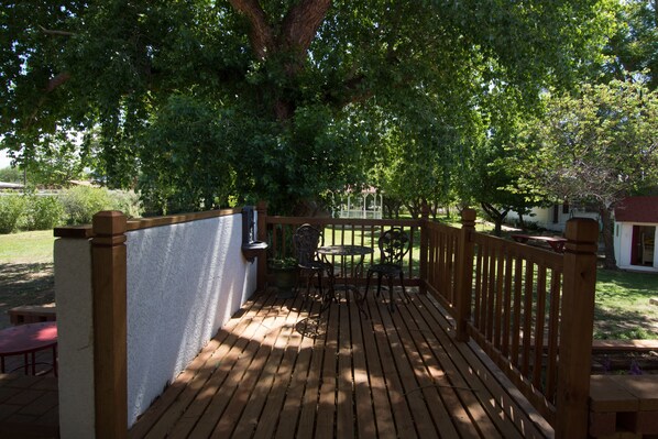 A wooden deck with a table and chairs, surrounded by a white wall and a wooden fence.