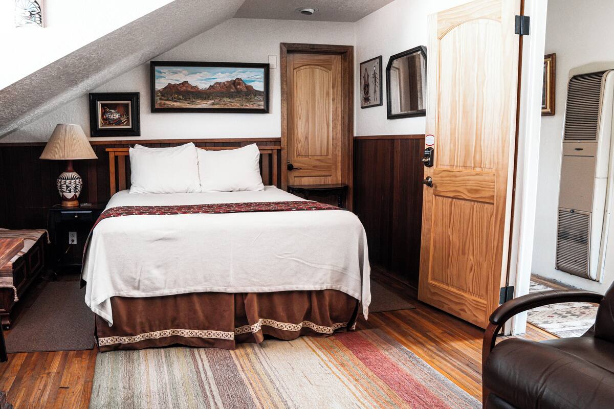 Une chambre à coucher avec un grand lit, des meubles en bois, un bureau et une porte.