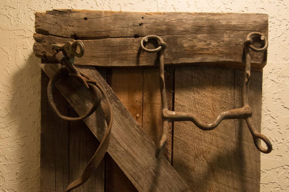 Un objet rustique en bois, fixé au mur, orné d’anneaux et de cordes en métal, qui pourrait être un élément décoratif ou un objet utilitaire.