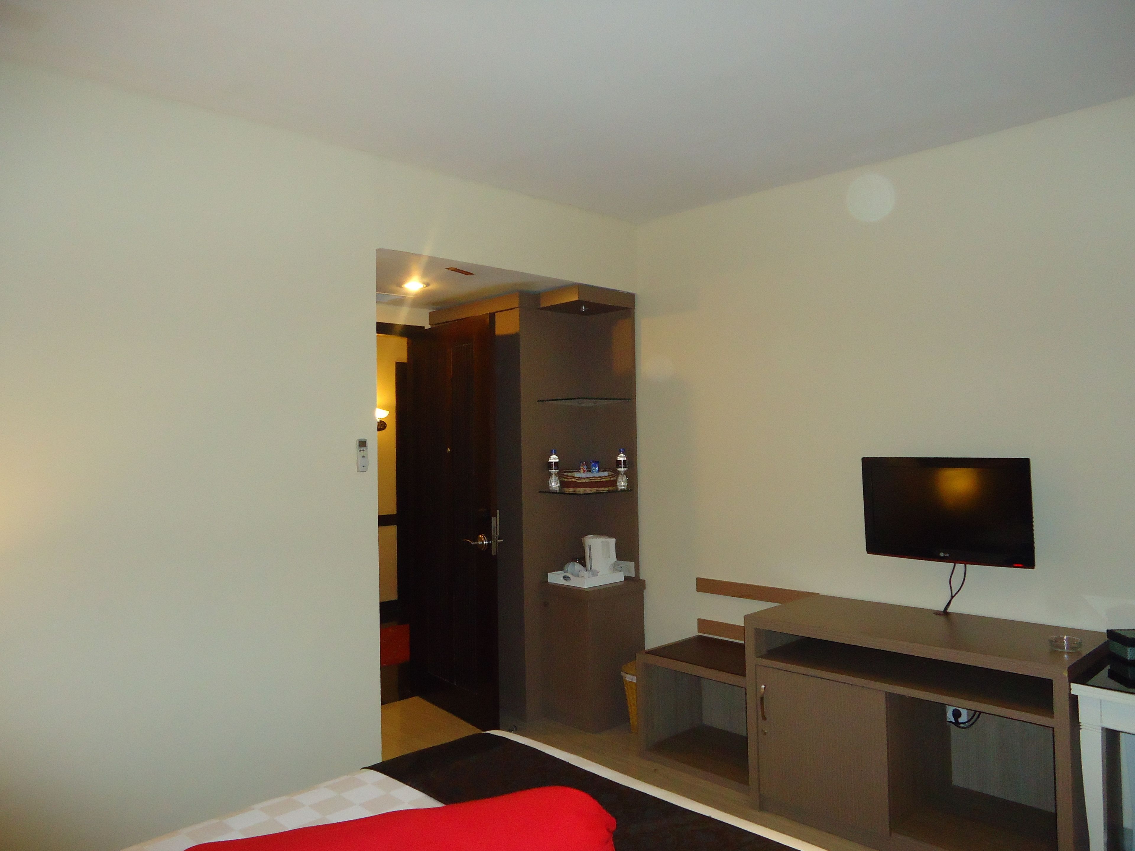 Una habitación de hotel con una cama, televisor, escritorio y armario.