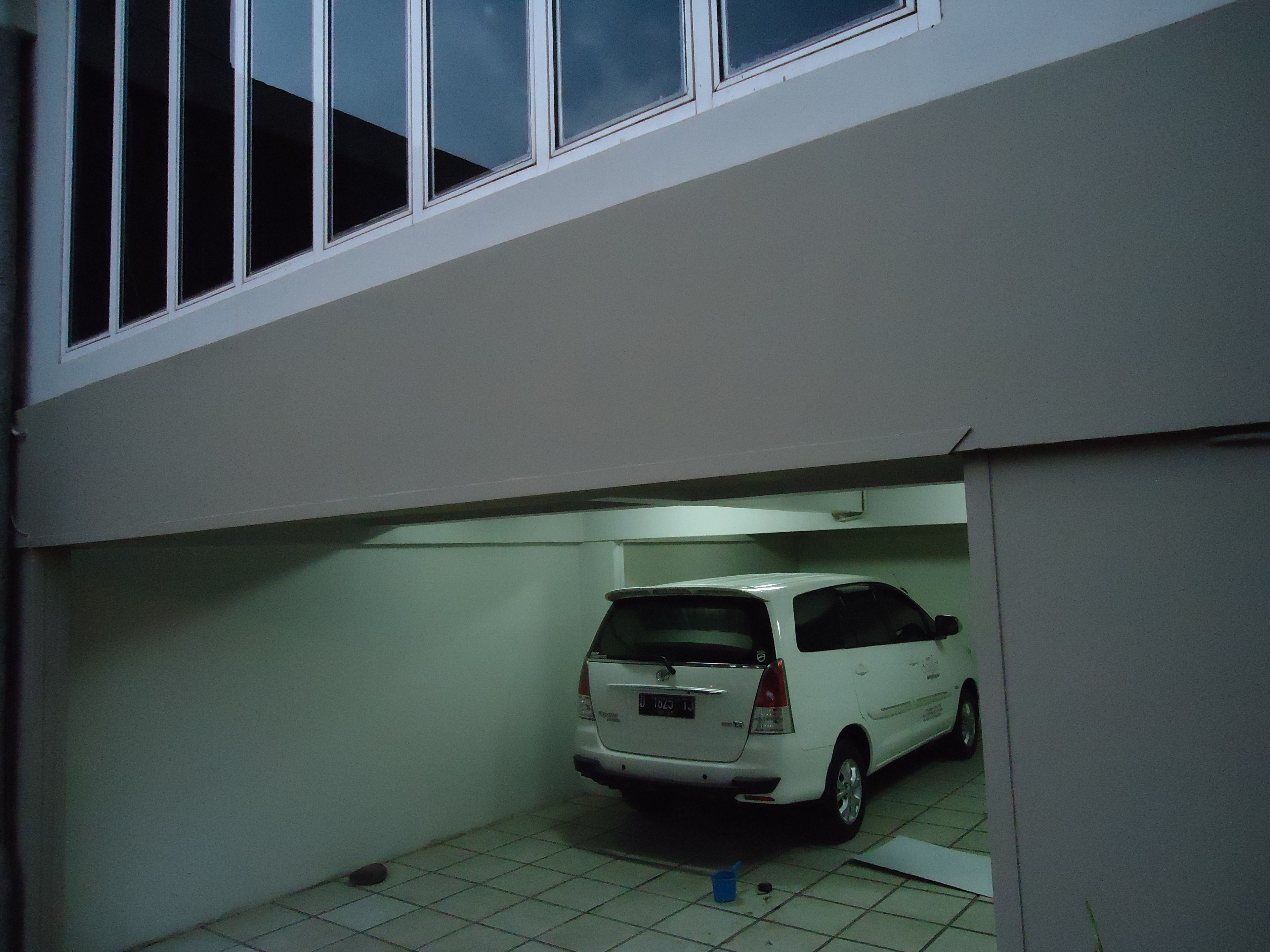 Um carro branco estacionado numa área de estacionamento coberta com chão em mosaico.